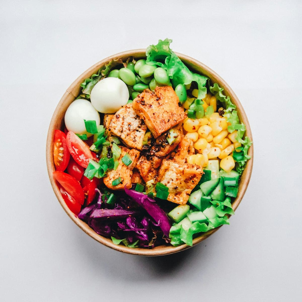 A grain bowl with tofu, egg, edamame and corn.